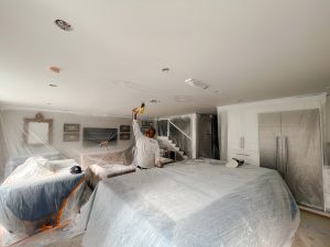 Interior painting preparation with furniture and cabinets fully protected using plastic sheeting